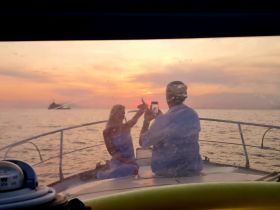 A couple captures a beautiful sunset while enjoying a romantic moment on a boat, perfect for memorable experiences on the water.