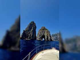 A stunning view of iconic rock formations from the bow of a boat, showcasing the breathtaking coastline and crystal-clear waters — perfect for exploring scenic destinations.