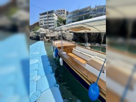 A beautifully crafted boat docked at a serene location, showcasing its elegant wooden interior and tranquil waters — perfect for a day out on the sea.