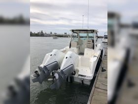 A sleek center console boat docked at the marina, showcasing its powerful twin engines and spacious design, perfect for fishing or day cruising.