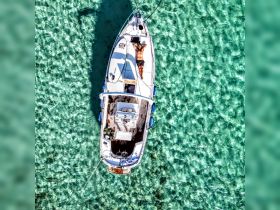 Aerial view of a person relaxing on the deck of a boat surrounded by stunning turquoise waters, capturing the essence of a perfect day on the water.