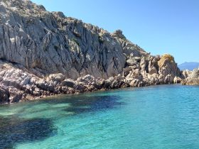 A stunning view of rocky cliffs meeting crystal-clear waters, showcasing the natural beauty of the coastline — perfect for scenic boat trips and exploration.