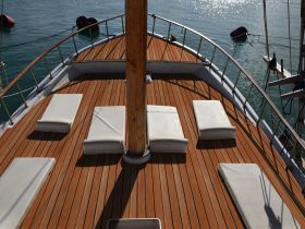 The spacious deck of a boat features comfortable lounge seating, perfect for relaxing and enjoying the serene waters.
