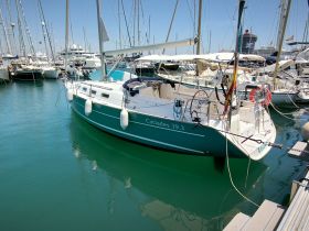 A beautiful Cyclades 39.3 sailboat docked in a marina, showcasing its sleek design and vibrant colors against the clear blue water.