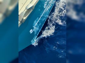 Close-up of a boat's hull cutting through deep blue waters, showcasing its sleek design and vibrant color — perfect for showcasing boat features.