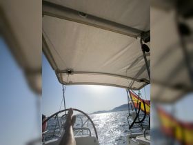 A relaxing view from the helm of a sailboat, showcasing a sunny day on the water with a scenic backdrop. Perfect for those seeking tranquility while sailing.