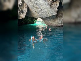 A joyful group enjoys swimming in a stunning cave with turquoise waters, perfect for snorkeling adventures and exploring hidden gems.