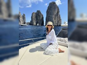 A woman enjoys the stunning views of iconic rock formations while relaxing on a boat, capturing the essence of a perfect vacation on the water.