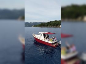 A lively group enjoys their time aboard a boat, celebrating with drinks and laughter against a stunning coastal backdrop.