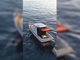 Aerial view of a stylish boat anchored in calm waters, showcasing its sleek design and inviting deck — perfect for leisurely outings on the water.