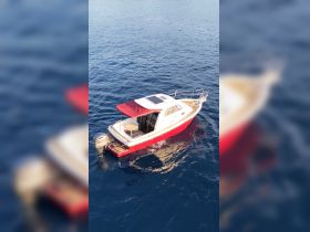 Aerial view of a stylish boat anchored in deep blue waters, showcasing its sleek design and inviting deck space.