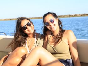 Two friends enjoy a sunny day on the boat, smiling and relaxing by the water — perfect for creating unforgettable memories on a boating adventure.