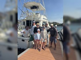 A cheerful group of family and friends poses together on the deck of a fishing boat, capturing a memorable moment before their adventure on the water.