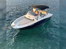 A man navigates a sleek boat through crystal-clear waters, showcasing the perfect blend of adventure and relaxation on the sea.