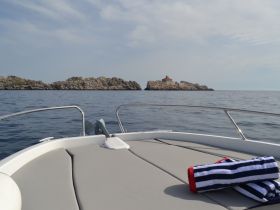 A serene view from the front of a boat, showcasing rocky islands in the distance under a clear sky — perfect for exploring coastal landscapes.