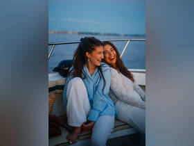 Two friends share a joyful moment on a boat, laughing together as they enjoy a sunset cruise — perfect for creating unforgettable memories on the water.