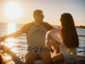 A couple enjoys a romantic moment on a yacht at sunset, capturing the essence of love and adventure on the water.