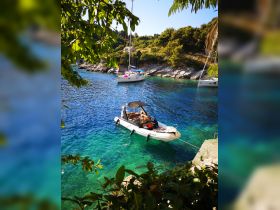 A scenic view of a speedboat docked in crystal-clear waters, surrounded by lush greenery and rocky shores, perfect for exploring hidden coves.