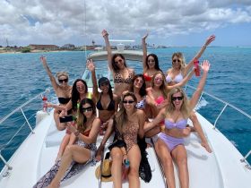 A lively group of friends celebrates on a boat, enjoying the sun and sea in stylish bikinis — perfect for a fun day out on the water.