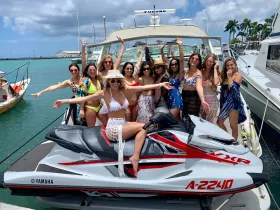 A lively group of friends celebrates on a jet ski at the marina, showcasing the perfect blend of fun and adventure on the water.