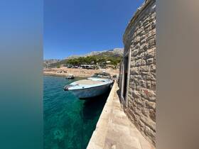 A sleek speedboat docked at a picturesque waterfront, surrounded by clear turquoise waters and scenic mountains, perfect for summer adventures.