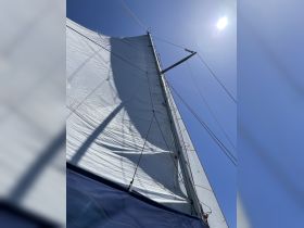 A close-up view of a sail on a sailboat, showcasing the intricate details of the rigging against a clear blue sky — perfect for sailing enthusiasts.
