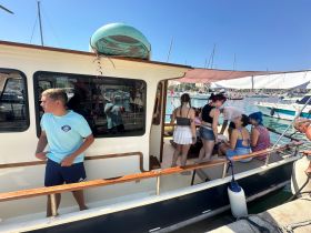A lively group of friends enjoys their time aboard a boat, capturing the essence of summer fun and celebration in a vibrant marina setting.