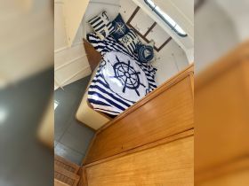 Cozy cabin interior featuring a beautifully designed bed with nautical-themed pillows, perfect for relaxing on a boat.