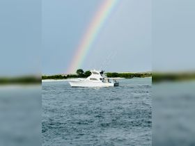 A fishing boat navigates through the ocean under a vibrant rainbow, creating a picturesque scene perfect for adventure and exploration on the water.