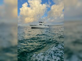 A sleek yacht navigates through shimmering waters under a dramatic sky, showcasing the perfect setting for a day on the ocean.