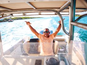 A joyful individual celebrates while steering a boat through vibrant waters, capturing the essence of fun on the water.