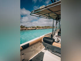 A detailed view of the helm area inside a boat, showcasing the console and seating, with a stunning turquoise water backdrop.