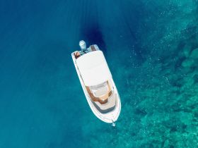 A stunning aerial view of a sleek boat gliding over crystal-clear waters, showcasing the beauty of marine adventures.