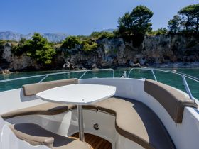 A cozy seating area inside a boat, featuring comfortable cushions and a table, perfect for relaxing while enjoying scenic views.