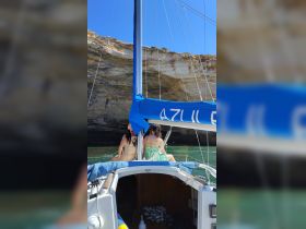 Two friends enjoy a scenic sailing experience on a boat, surrounded by stunning rock formations and clear waters, perfect for memorable adventures on the sea.
