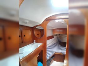 Interior view of a cozy boat cabin featuring a sink and a comfortable sleeping area with striped bedding, ideal for relaxing during voyages.