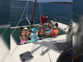 A lively group enjoys a sun-soaked day on a catamaran, relaxing and sipping drinks while soaking up the sun — the perfect backdrop for a fun day at sea.