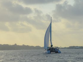 A lively group enjoys a sailing adventure on a catamaran during sunset, creating the perfect backdrop for memorable moments on the water.