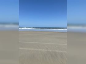 A serene beach scene with waves gently lapping at the shore under a clear blue sky, perfect for relaxation and beach activities.