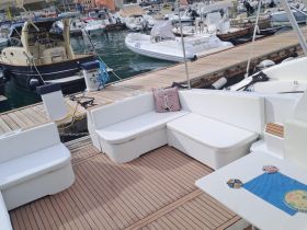 A cozy interior seating area on a boat, featuring comfortable benches and a small table, perfect for relaxing while enjoying the marina views.
