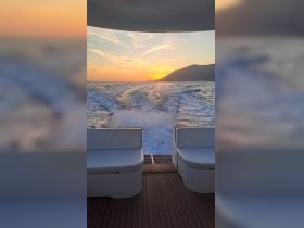 A stunning sunset view from the back of a boat, showcasing the tranquil ocean and distant mountains — perfect for evening cruises.