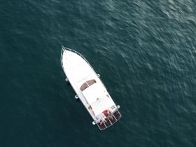 Aerial view of a boat cruising through calm waters, showcasing a group enjoying their time on the water — perfect for adventure seekers and leisure trips.
