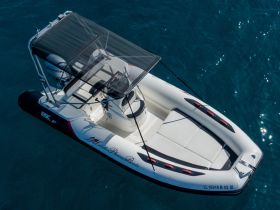 Aerial view of a sleek speedboat anchored in clear waters, showcasing its modern design and spacious seating — perfect for thrilling adventures on the water.