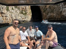 A group of friends enjoys a sunny day on a boat, surrounded by stunning coastal cliffs — perfect for summer adventures and memorable outings.