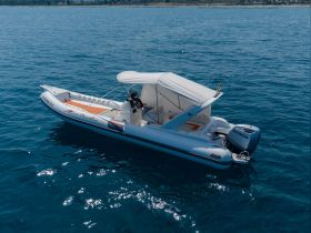 A sleek speedboat glides through clear blue waters, showcasing its elegant design and spacious deck, perfect for thrilling adventures on the sea.