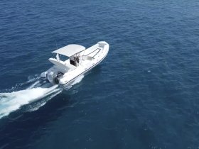 A sleek speedboat cruising through clear blue waters, showcasing its design and performance on the open sea.