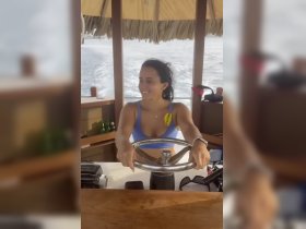 A woman joyfully steers the boat from the helm, showcasing the cozy interior of the cabin — perfect for navigating the open waters.