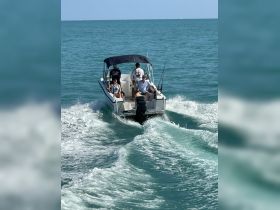 A group enjoys a thrilling fishing trip aboard a boat, navigating through vibrant turquoise waters — perfect for adventure seekers.