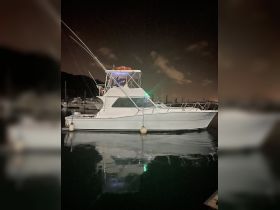 A fishing boat docked at night, illuminated by lights, showcasing its sleek design and tranquil surroundings in the marina.