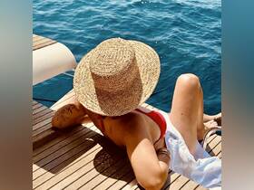 A woman relaxes on the deck of a boat, enjoying the sun and the serene blue waters — a perfect moment for leisure and tranquility on the water.